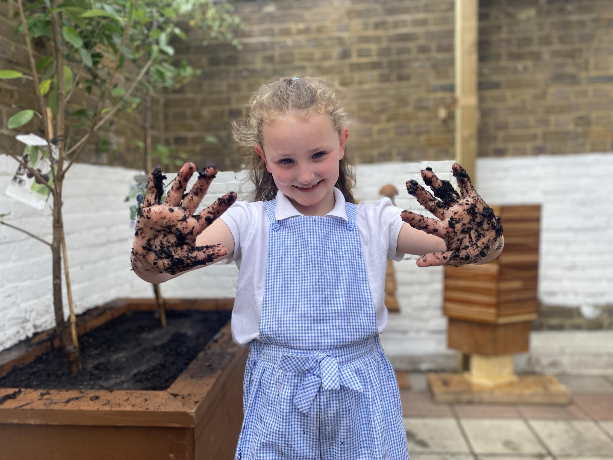 Young girl in school uniform with muddy hands from the new orchards